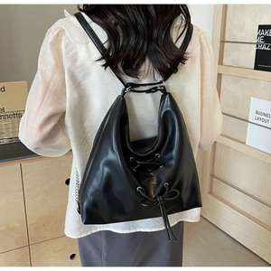 Rear view of black leather backpack with eyelet details and lace-up bow on model