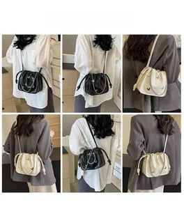 Detail view of ruched drawstring bag with metal butterfly and chain strap on models