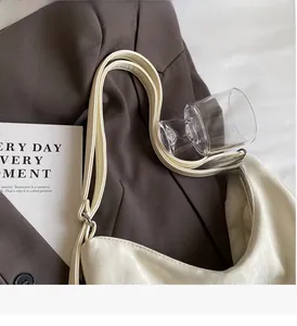Detail of cream crescent bag with double straps and silver hardware on a dark blazer