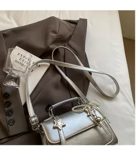 Détail du sac carré argenté avec boucle étoile et pendentif nœud en perles élégant