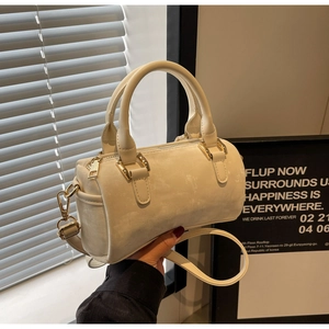 Detailed macro of cream Boston bag with matte leather texture and gold hardware