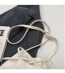 Détail de la bandoulière réglable et texture cuir d'un sac seau minimaliste crème