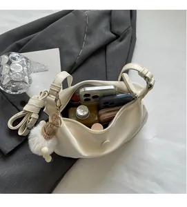 Detail view showing large interior capacity of cream crescent bag with plush charm