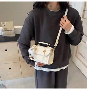 Minimalist beige crossbody bag with top handle and cute plush charm detail in lifestyle view