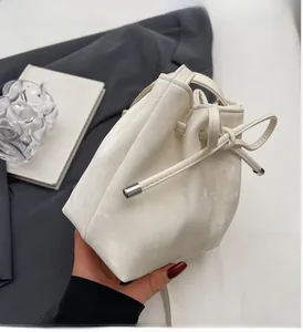 Gros plan du sac seau crème minimaliste avec cordon de serrage et détail de nœud argenté