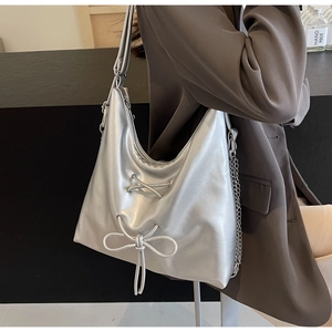 Detail of silver metallic hobo bag featuring lace-up ribbons and side chain ornament