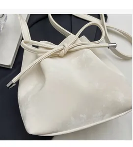 Détail du sac seau blanc crème avec nœud de serrage et embouts de sangle argentés