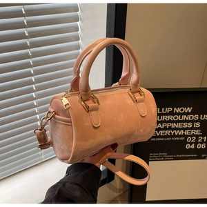 Detail of pink velvet Boston bag with gold hardware and dual top handles held by person