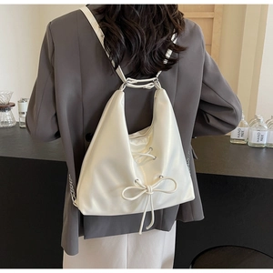 Detail of cream white PU leather tote with drawstring bow and wide strap on model