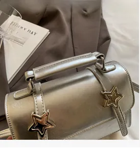 Gros plan du sac à main argenté avec boucles en étoile et poignée supérieure renforcée