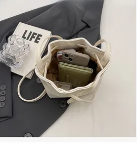 Détail de l'intérieur spacieux du sac seau crème avec portefeuille et smartphone