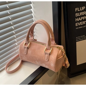 Detail of pink cylindrical Boston bag featuring matte suede texture and gold hardware