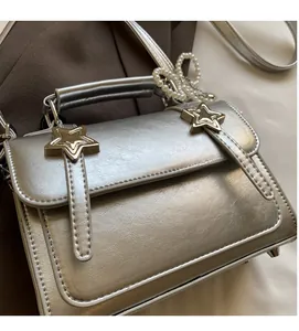 Détails du sac à main en cuir argenté avec étoiles dorées et breloque en perles