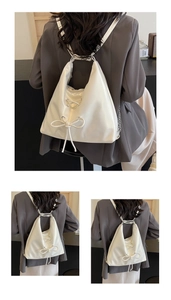Detail of white hobo backpack with lace-up ribbon and bow on grey suit blazer