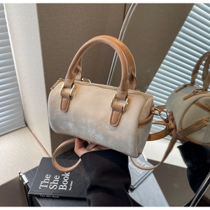 Close-up of beige suede Boston bag with brown leather handles and golden metal hardware