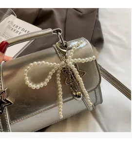 Détail du sac argenté avec nœud en perles et pendentifs en forme d'étoiles