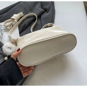 Detail of off-white leather shoulder bag with plush pom-pom charm and adjustable strap