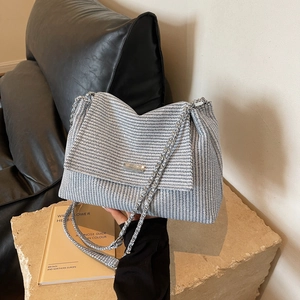 Blue and white woven knit chain bag on stone surface with minimalist fashion aesthetic