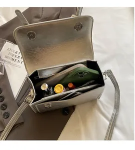 Aménagement intérieur du sac argenté montrant l'espace pour téléphone et maquillage