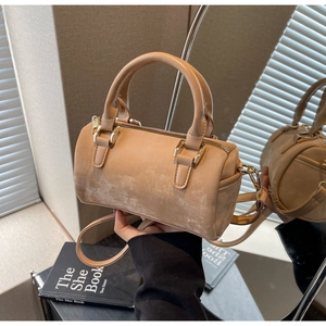 Close-up of a beige Boston handbag with matte leather texture and golden zipper