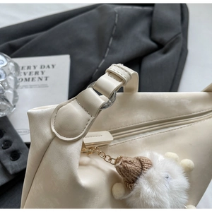 Detail of beige leather dumpling bag with silver zipper and cute lamb plush charm