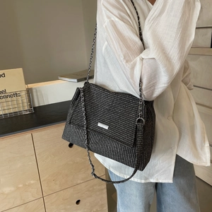Vintage gray woven shoulder bag with silver chain strap worn by a model in a minimalist room