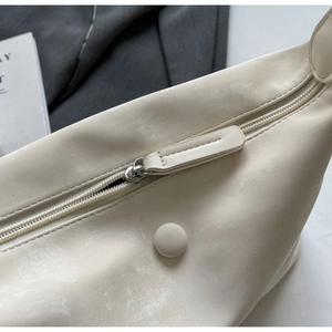 Detail of cream leather bag showing smooth zipper and vintage textured finish
