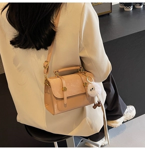 Chic beige crossbody bag with plush charm styled with a white blazer for a commute look