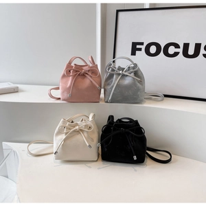 Détail de sacs seaux minimalistes en rose, argent, blanc et noir avec des nœuds coulissants