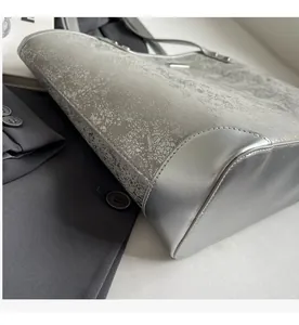 Close-up of silver-gray tote bag with metallic reinforced corners and stitch detail