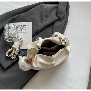 Cream white dumpling bag with adjustable strap and cute fur pompom charm accessory