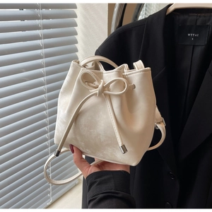 Gros plan sur un sac seau crème avec un grand nœud et une fermeture à cordon