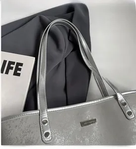 Detail of silver metallic tote bag showing smooth handles and glossy faux leather texture