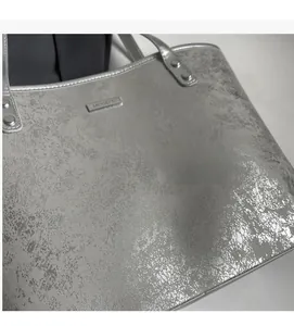 Detail of silver tote bag with metallic cracked texture and brand name plate