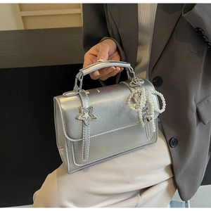 Détail du sac à main argenté métallisé avec boucle étoile et breloque cœur en perles