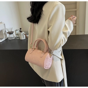 Detail shot of a pink Boston pillow bag worn by a model in a cozy cafe setting