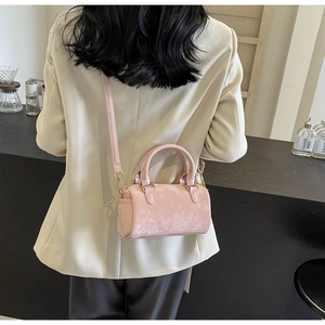 Pink suede Boston bag shown as a crossbody in a natural cafe setting for women