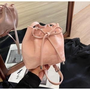 Détail du sac seau rose à cordon avec texture métallique et nœud décoratif élégant