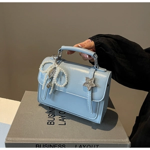 Détail du petit sac carré bleu clair avec noeud en perles et étoile argentée