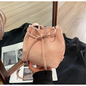 Détail du mini sac seau rose montrant la texture mate et la fermeture à cordon à nœud
