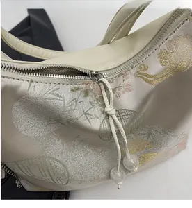 Detail of smooth metal zipper and floral embroidery on women's neo-chinese tote bag