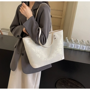 Detail of cream tote bag featuring metallic marble texture and reinforced rivets
