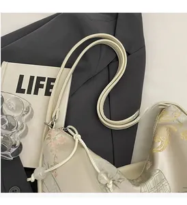 Close-up of beige silk jacquard handbag with traditional Chinese floral and bird patterns
