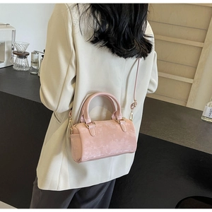 Detail of pink suede Boston bag worn crossbody with elegant beige blazer outfit