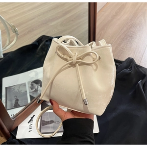 Détail d'un sac seau beige crème avec cordon de serrage et nœud décoratif en cuir