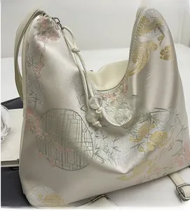 Detail of floral jacquard silk fabric on a white crossbody bag with drawstring closure