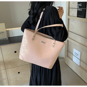 Detailed view of peach pink large tote bag with shimmering metallic finish worn on shoulder
