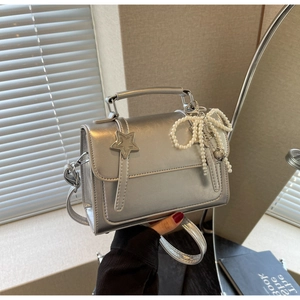 Détail du sac carré argenté métallisé avec boucle étoile et breloque perle nœud