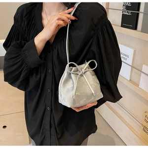 Détail du sac seau argenté à cordon avec nœuds décoratifs et fine bandoulière