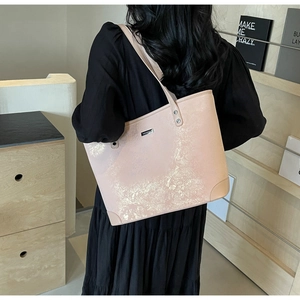 Detail of light pink tote bag with gold texture and silver brand logo worn by model